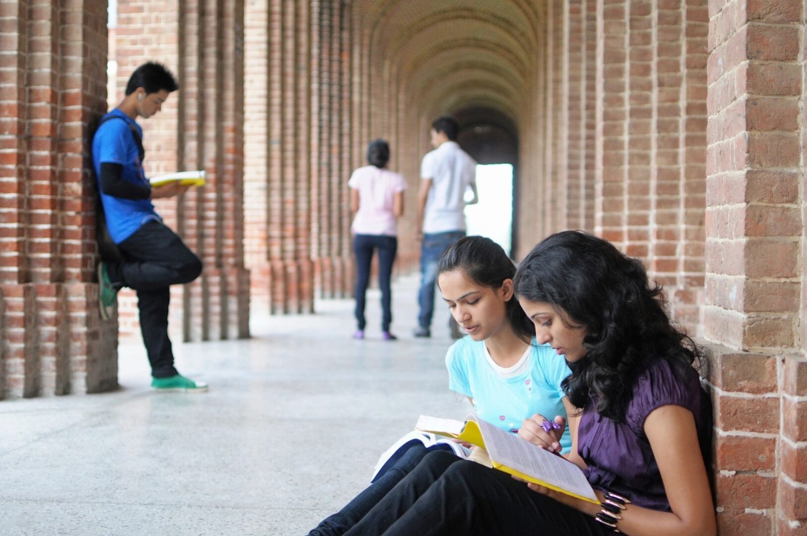 Two students are sitting on the floor reading.