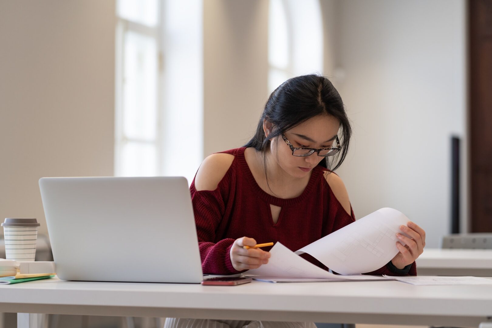 A woman sitting at a table with papers and a laptop.