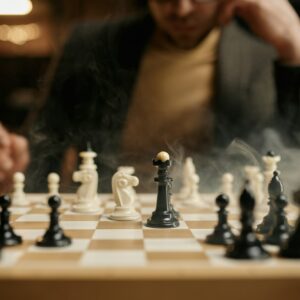 Closeup view on chessboard in smoke with chess player on blurred background