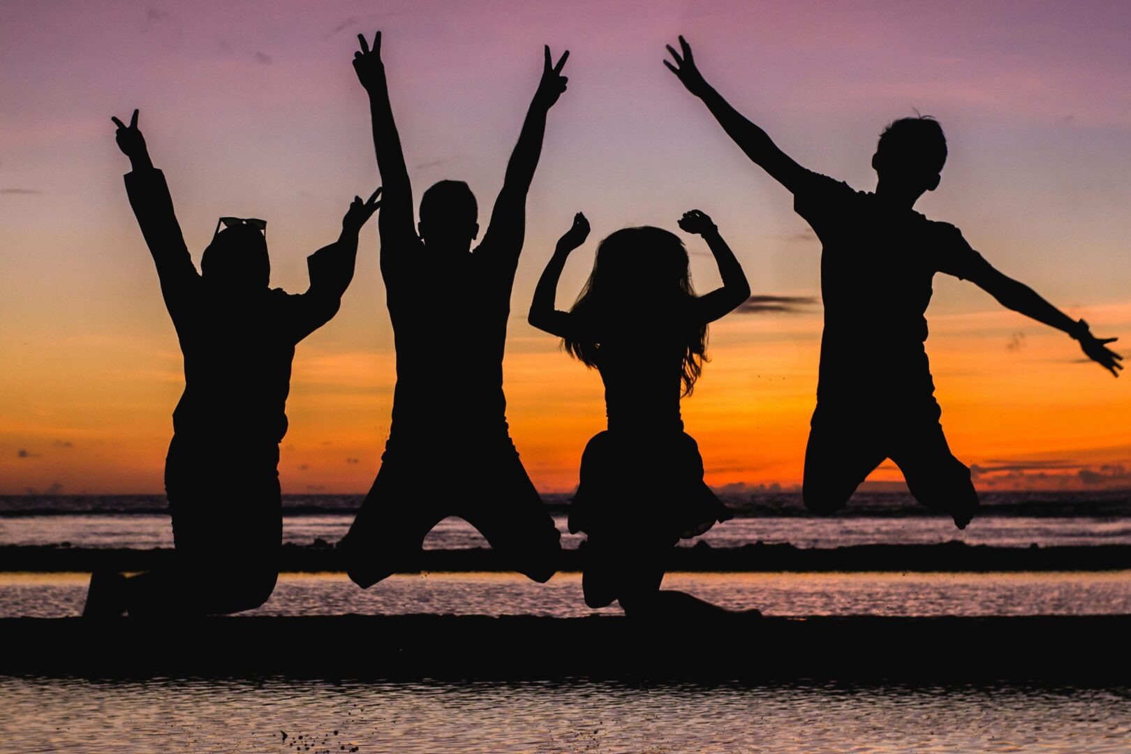 A group of people jumping in the air at sunset.