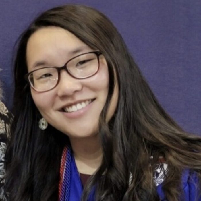 A woman with long hair and glasses smiling.
